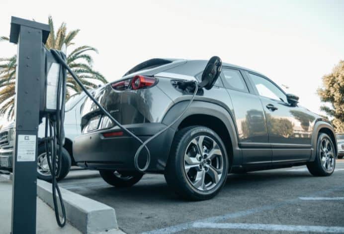 This is a picture of the back of an electric vehicle that is plugged into a charger.