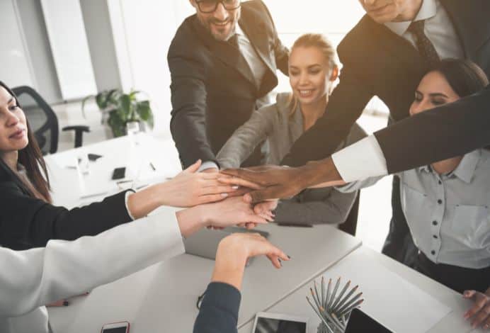 A photo of 5 people putting their hands together.